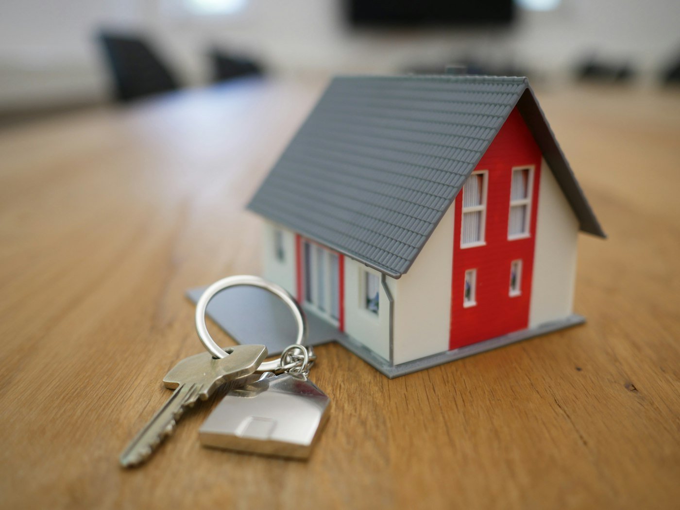 A set of keys and a small model house on a wooden table